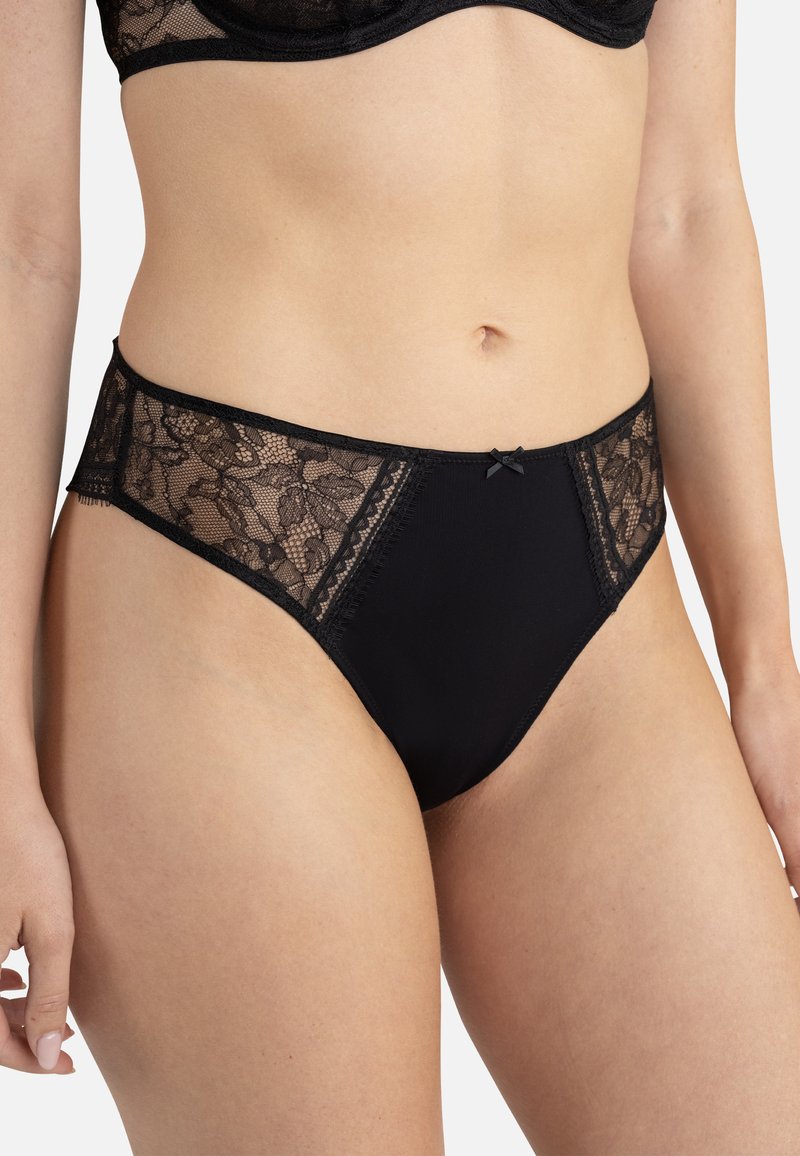 Culotte noire avec des panneaux latéraux en dentelle délicate, une taille lisse et un petit nœud sur le devant. Tissu extensible pour le confort.