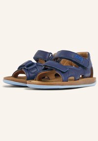 Sandali blu in pelle con doppie chiusure a strappo in Velcro, design aperto sulla punta, soletta beige e suola in gomma blu chiaro. Materiali resistenti con dettagli fustellati.