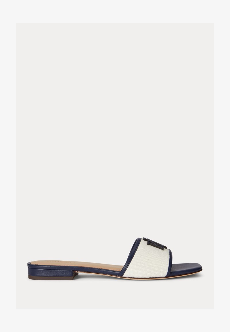 Sandale plate à semelle et talon bleu marine, large bride en tissu blanc, et boucle décorative noire sur le dessus.