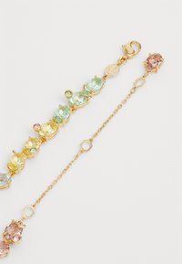 Gold-tone bracelet featuring multi-colored oval and round stones in pale green, yellow, and pink. Secure lobster clasp with chain extender.