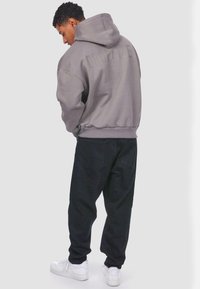 Gray hoodie with embossed "DROPSIZE" text on the back, paired with black pants and white sneakers, featuring a relaxed fit and smooth texture.