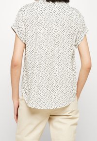 Korte mouwen, lichtbeige shirt met een bloemenpatroon in marineblauw en donkergroen, met een relaxte pasvorm en een ronde zoom.