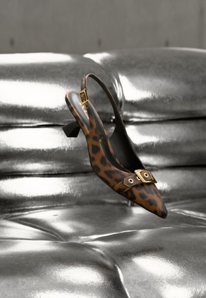 Leopardikuvioinen slingback-kenkä, jossa on terävä kärki, kultaiset metalliosat ja pieni blokki-korko, asetettuna kiiltävän metallipinnan päälle.