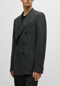 Double-breasted dark grey blazer with a textured finish, black buttons, and a chest pocket; tailored fit and notched lapels.