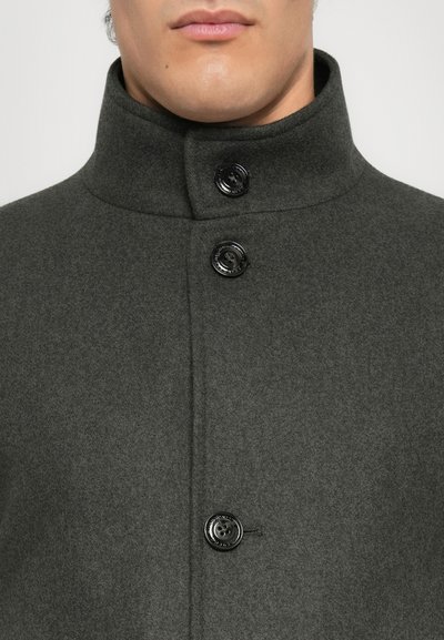 Manteau en laine gris foncé avec un col haut, trois boutons noirs et une texture lisse. Vue en gros plan se concentrant sur la partie supérieure.