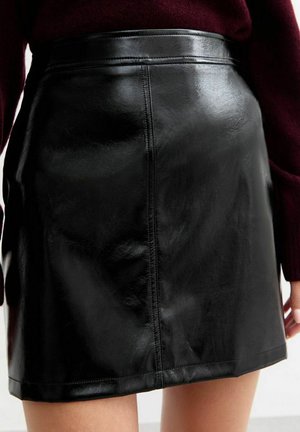 Falda corta de cuero negro con una textura suave, de cintura alta y con costuras visibles a lo largo de las costuras. Sin otras características notables.