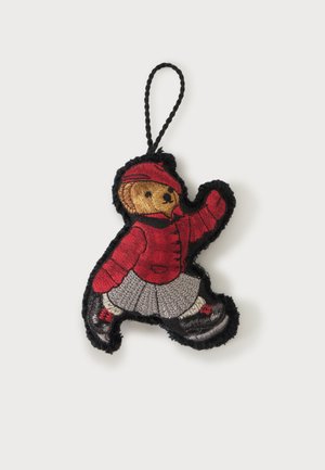 Porte-clés ours en peluche avec veste rouge, jupe grise, chaussures noires et casquette rouge, souligné par une couture noire sur fond blanc.