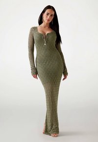 Long-sleeve, form-fitting dress in olive green knit fabric with diamond pattern and adjustable neckline. Features long sleeves and a straight cut.