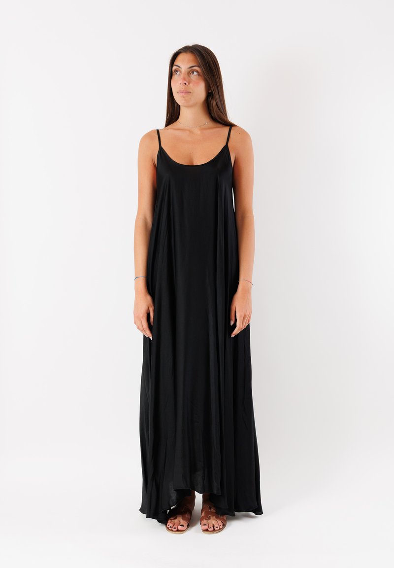 Vestito maxi nero senza maniche in tessuto morbido, caratterizzato da una vestibilità ampia, scollatura arrotondata e spacchi laterali, abbinato a sandali marroni.