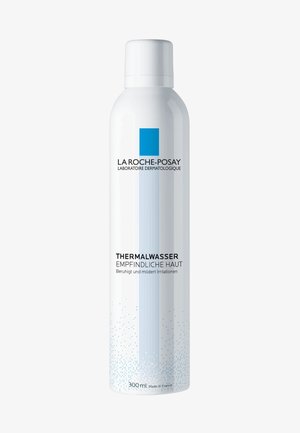 White aerosol can with a blue triangle logo and black text, labeled "Thermalwasser Empfindliche Haut," 300 ml, featuring a textured design.