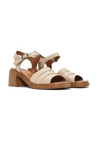 Sandali in pelle beige con design open-toe, fasce larghe e tacco a blocco. Presentano una cinghia alla caviglia regolabile e dettagli cuciti.