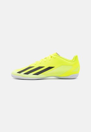 Zapatillas deportivas amarillas con detalles en negro, que presentan un diseño elegante, paneles de malla texturizada, puntera redonda y suela de goma.