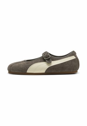 Grijze suède platte schoen met een witte streep aan de zijkant en een verstelbare gespband over de bovenkant.