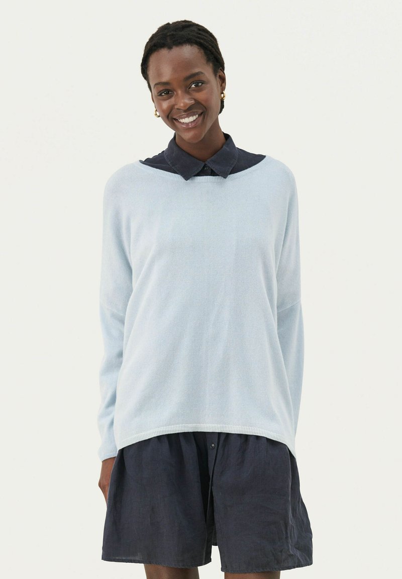 Himmelblauer Pullover mit entspannter Passform, langen Ärmeln und Rundhalsausschnitt, über einem dunkelblauen Kragenkleid getragen.