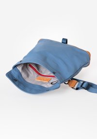 Borsa impermeabile blu con un'accortezza beige, tracolla regolabile e interno foderato con un motivo a quadri grigi e tasca con zip rossa.