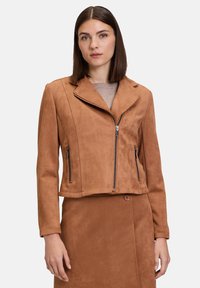 Brown faux suede cropped jacket with a notched collar, two zippered pockets, and a smooth texture. Paired with a matching brown skirt.