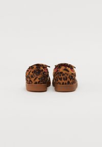 Brune leopardmønstret sko med en blød ruskindsstruktur, der har en flad sål og et lavprofildesign, accentueret med en glat tan gummi bund.