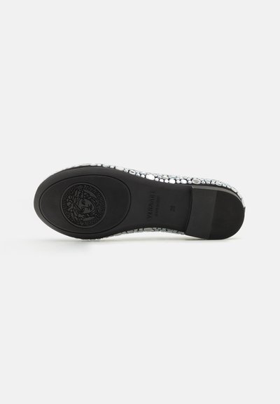Suela negra con diseño texturizado, rodeada de un brillante acento plateado de pequeñas piedras, con logotipo en relieve y costuras detalladas.