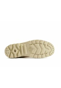 Sole di sneaker beige chiaro caratterizzata da un motivo di grip testurizzato con battistrada pronunciato, fori di drenaggio e forme contornate per una migliore trazione.
