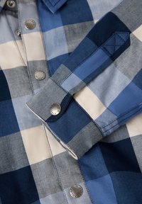 Blauw geruit shirt met verschillende tinten blauw en wit, vaste knopen, een kraag en gedetailleerde stiksels op de manchetten.