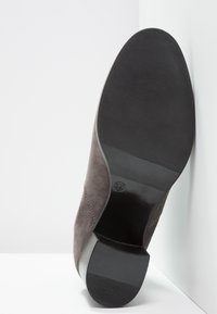 Szare zamszowe buty na płaskiej gumowej podeszwie, z zaokrąglonym noskiem i lekko podniesionym czarnym obcasem. Czyste szwy wzdłuż krawędzi.