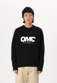 Suéter negro de canalé con cuello redondo y hombros caídos, que presenta un audaz texto gráfico en blanco "OMC OFF-TRACK MEMBERS' CLUB" en la parte frontal.