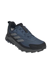 Zapato exterior azul oscuro con parte superior de tela texturizada, punta de goma negra y acentos grises. Diseñado para ofrecer tracción con una suela resistente.