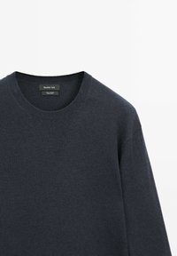 Maglione in lana blu navy con scollo rotondo, maniche lunghe e una texture morbida. Presenta un'etichetta interna con i dettagli del marchio.