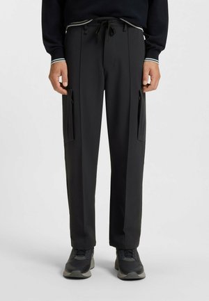 Black, lightweight trousers with a relaxed fit, featuring side pockets and a drawstring waistband. Smooth texture, suitable for casual wear.