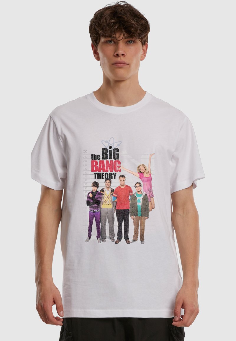 Νεαρός άνδρας με λευκό T-shirt που έχει τυπωμένο το καστ της σειράς The Big Bang Theory και τον τίτλο της εκπομπής μπροστά.