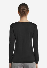 Svart långärmad tröja med rund halsringning och en slät textur. Har åtsittande ärmar och en lätt stretch för komfort.