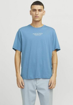 Svetlo modré tričko s krátkymi rukávmi vyrobené z bavlny, s bielym logom „JACK & JONES PREMIUM“ na hrudi. Jednoduchý, voľný strih.