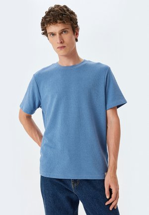 Blauw T-shirt met korte mouwen, gemaakt van gevarieerd materiaal, met een ronde hals en rechte zoom. In combinatie met donkerblauwe jeans.