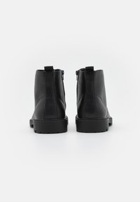 Botas de tobillo de cuero negro con una textura suave, que cuentan con cierre de cremallera y una suela de goma robusta para un mejor agarre.