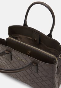 Brun quiltad läderhandväska med dubbla handtag, guldfärgad dragkedjestängning och inre fickor. Har en diskret logotyp på framsidan.