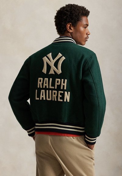 Zielona wełniana kurtka typu varsity z białym haftowanym logo "NY" oraz napisem "RALPH LAUREN". Posiada prążkowany kołnierz i mankiety w paski.