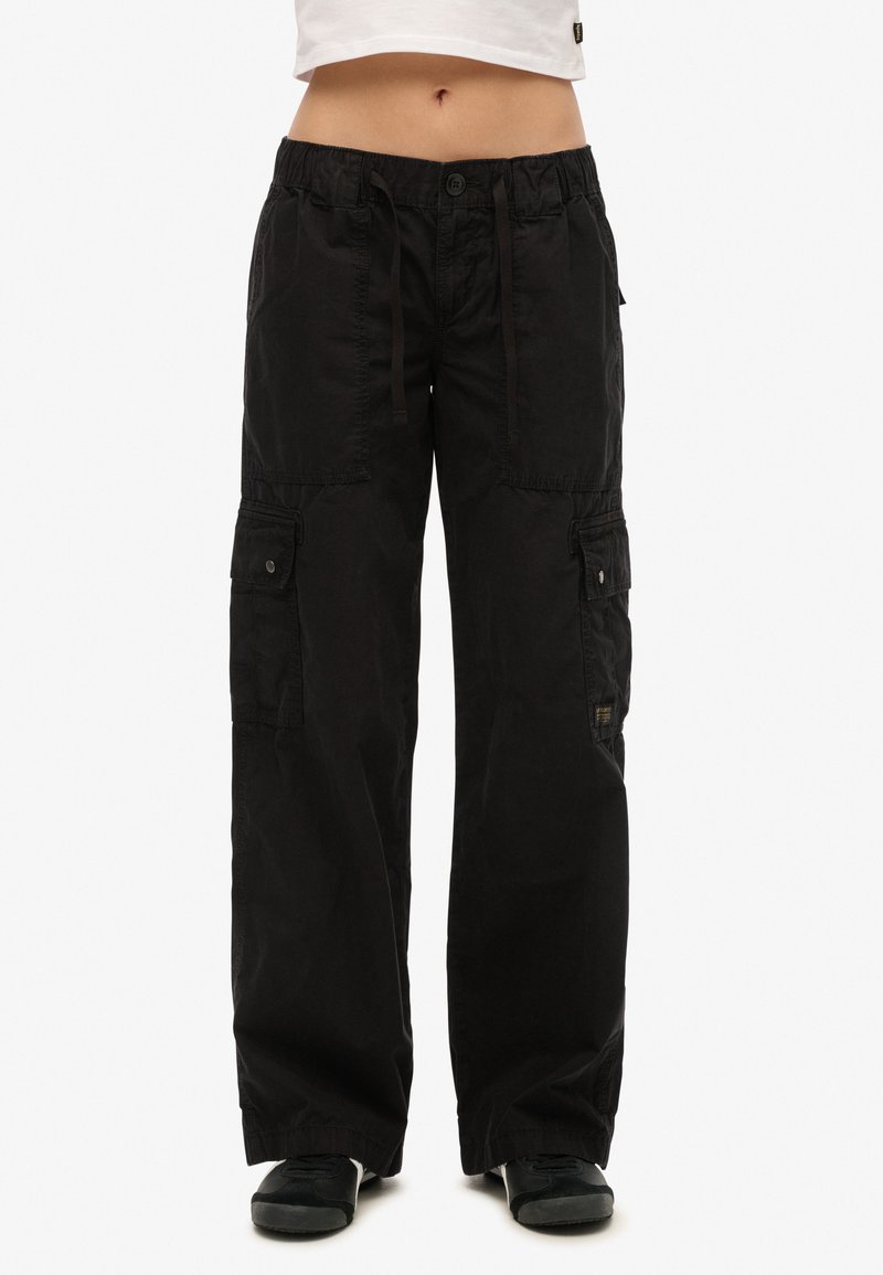 Schwarze Cargo-Hosen mit lockerer Passform, elastischem Bund, Kordelzugverschluss und mehreren seitlichen Taschen mit Knopfakzenten.