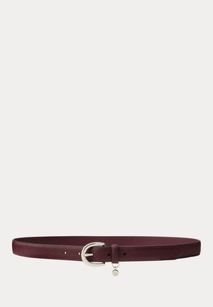 Ceinture en cuir texturé rouge foncé avec boucle arrondie argentée et petit pendentif circulaire suspendu près de la boucle.