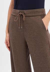 Braune Jogginghose mit weicher Textur, elastischem Bund, Kordelzugverschluss und seitlichen Taschen.