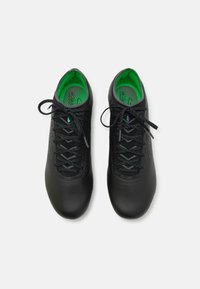 Baskets de sport noires avec un dessus texturé, semelles intérieures vertes contrastantes et lacets noirs. Présente un design ajusté et une semelle en caoutchouc courbée.