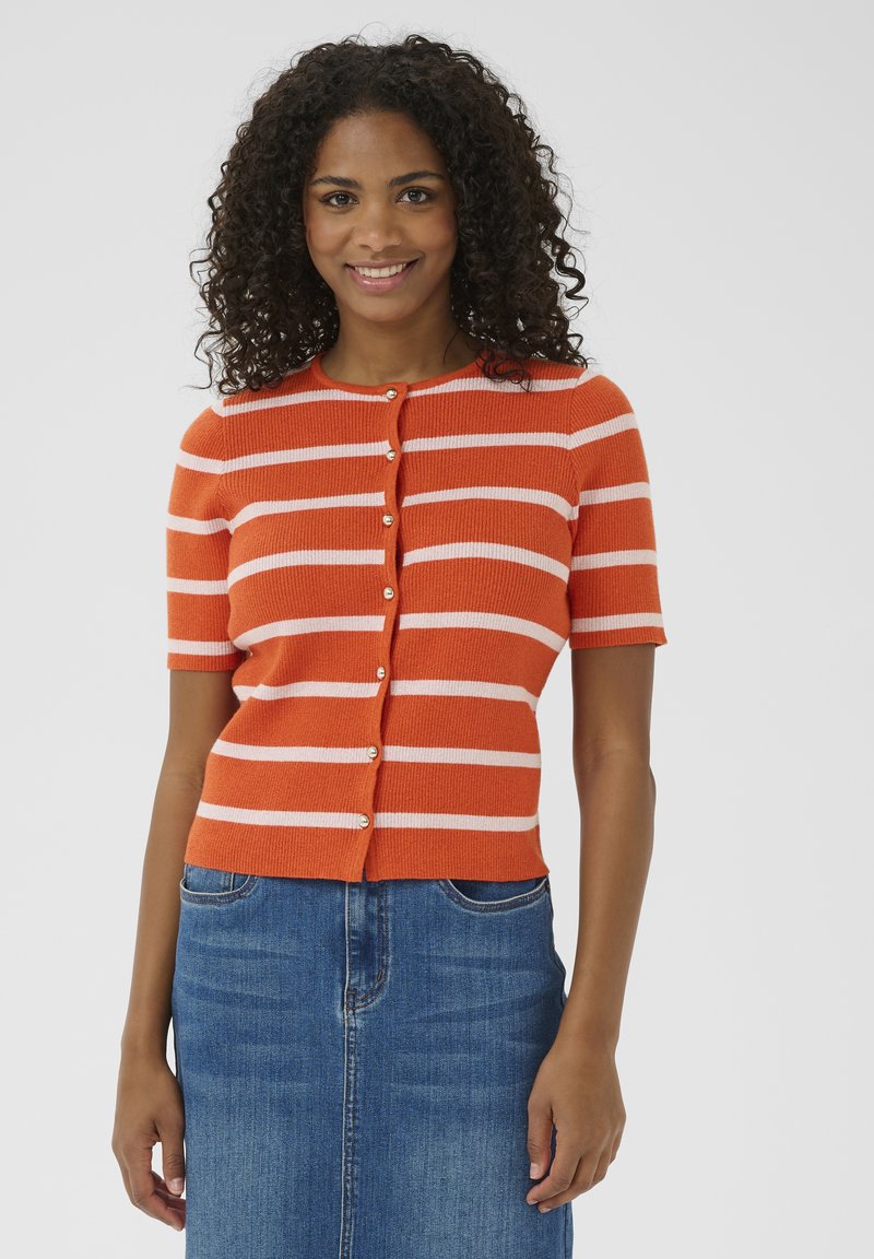 Cardigan à manches courtes rayé orange avec des rayures blanches et des boutons dorés, associé à une jupe en jean. Texture tricotée douce.