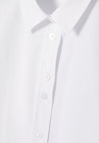 Hvid skjorte med knapper, der har en klassisk krave, glat stof, seks-knaps placket med runde, gennemsigtige knapper og et rent design.