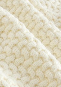 Gestrickte Decke aus weicher, cremefarbener Wolle; mit einem strukturierten, geflochtenen Muster und ausgeprägtem, erhabenem Stich.
