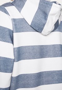 Sweat à capuche avec larges rayures horizontales alternant tissu blanc et bleu chiné.