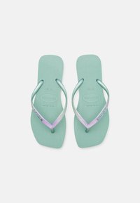 Tongs vert menthe avec des semelles texturées et flexibles, et des lanières brillantes en dégradé de argent et lavande. Comprend un logo sur une lanière.