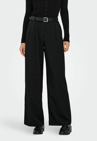 Sorte vidbukse med tynne striper og høy midje, med svart belte og glatt tekstur. Kombinert med svarte sko.