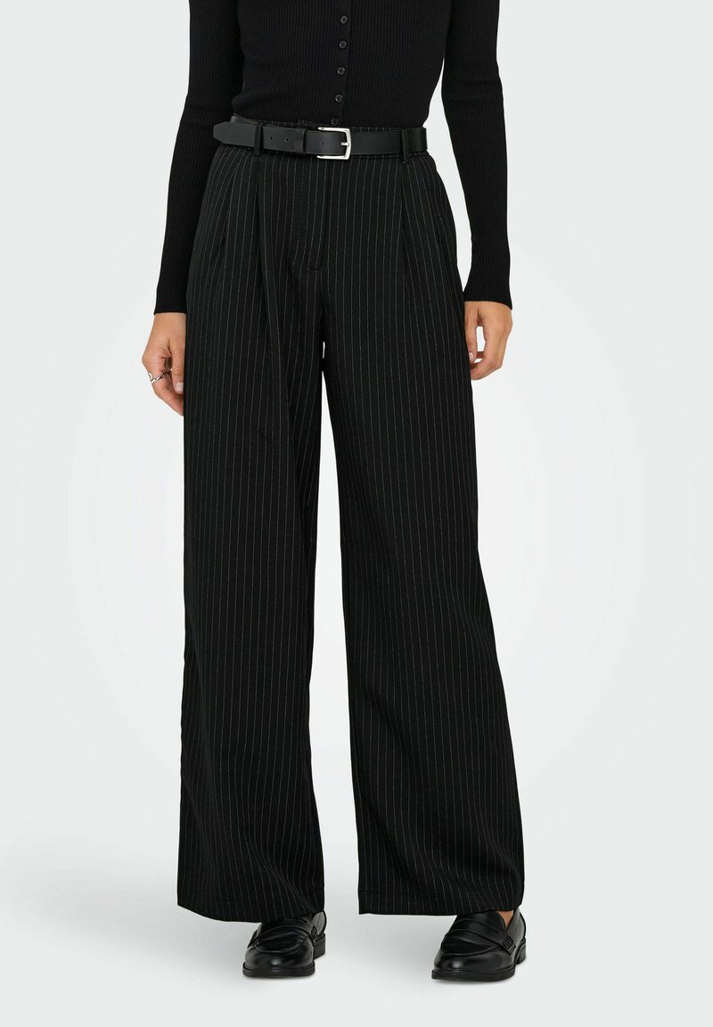 Sorte vidbukse med tynne striper og høy midje, med svart belte og glatt tekstur. Kombinert med svarte sko.