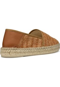 Espadrille in pelle marrone e paglia intrecciata con suola in juta e cuciture laterali. La parte superiore ha una texture liscia e una forma arrotondata.