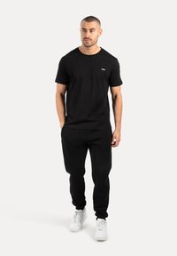 Sort bomuld t-shirt med korte ærmer, kombineret med sorte joggers. Afslappet design suppleret med hvide sneakers. Lille logo på brystet.