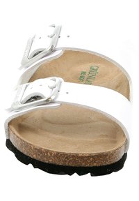 Sandal bianca con due cinghie e fibbie argentate, suola in sughero e battistrada in gomma nera. L'interno presenta una superficie liscia e imbottita beige.
